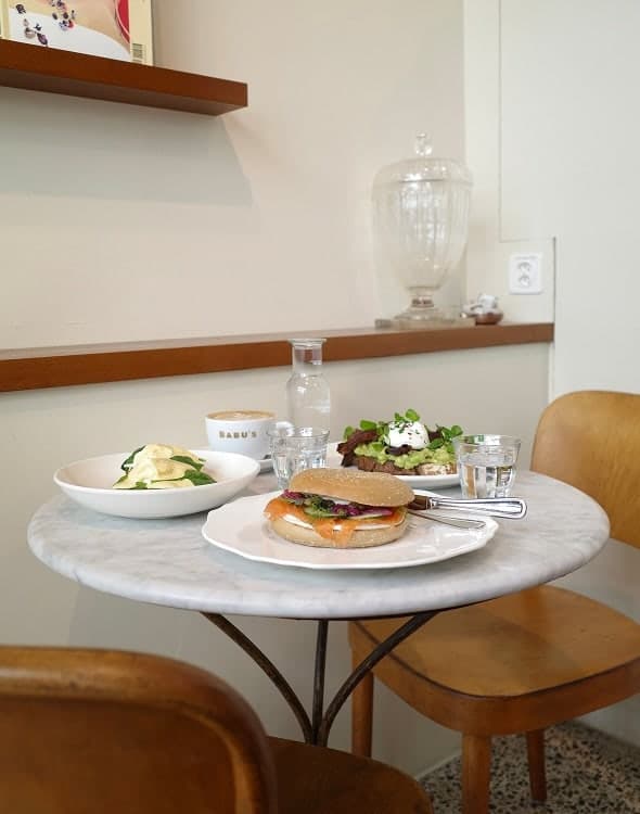 Ein Brunchteller mit Lachsbagel, Avocado und pochiertem Ei auf einem Marmortisch bei Babu's