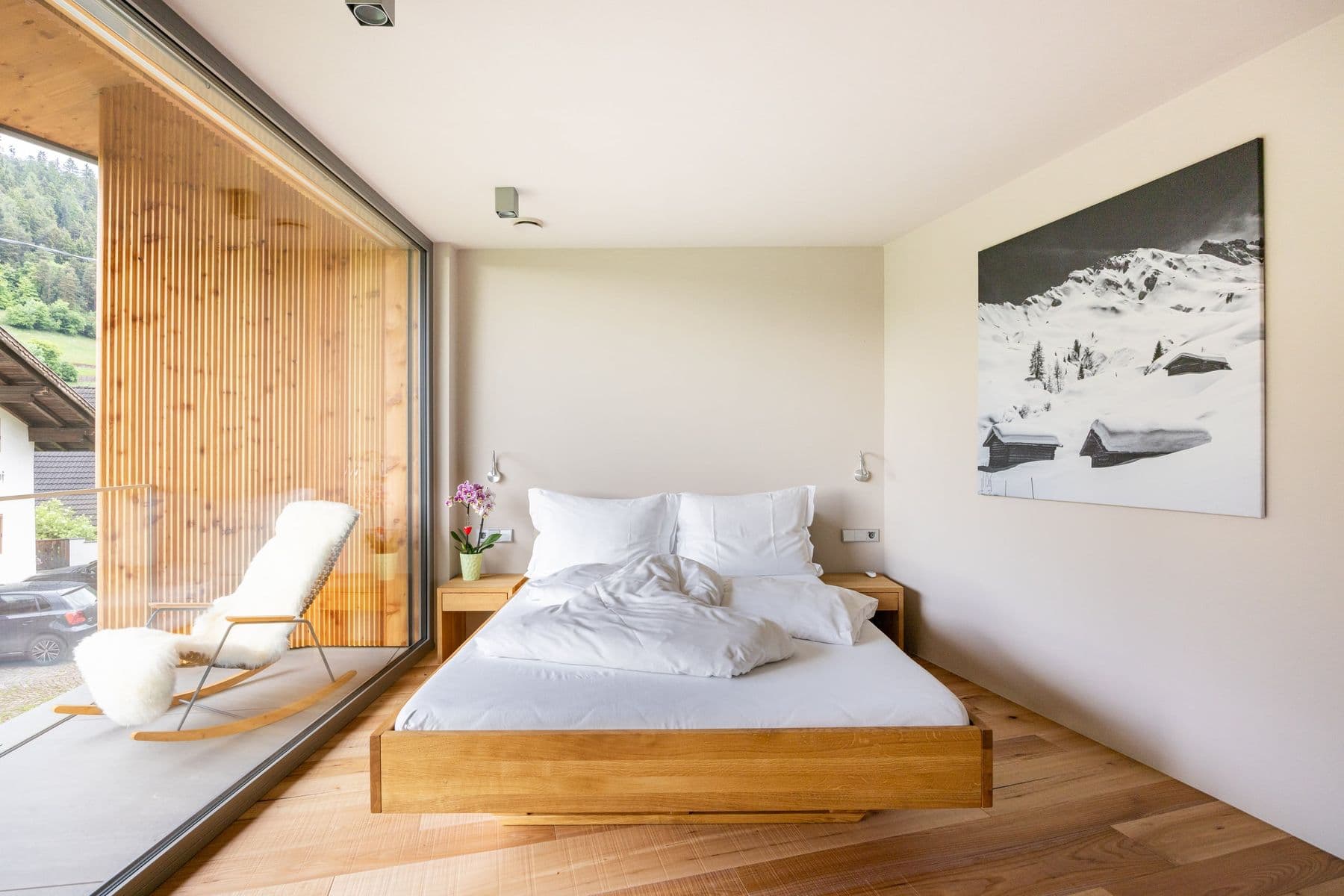 Queensize-Bett aus Holz vor einer Glaswand