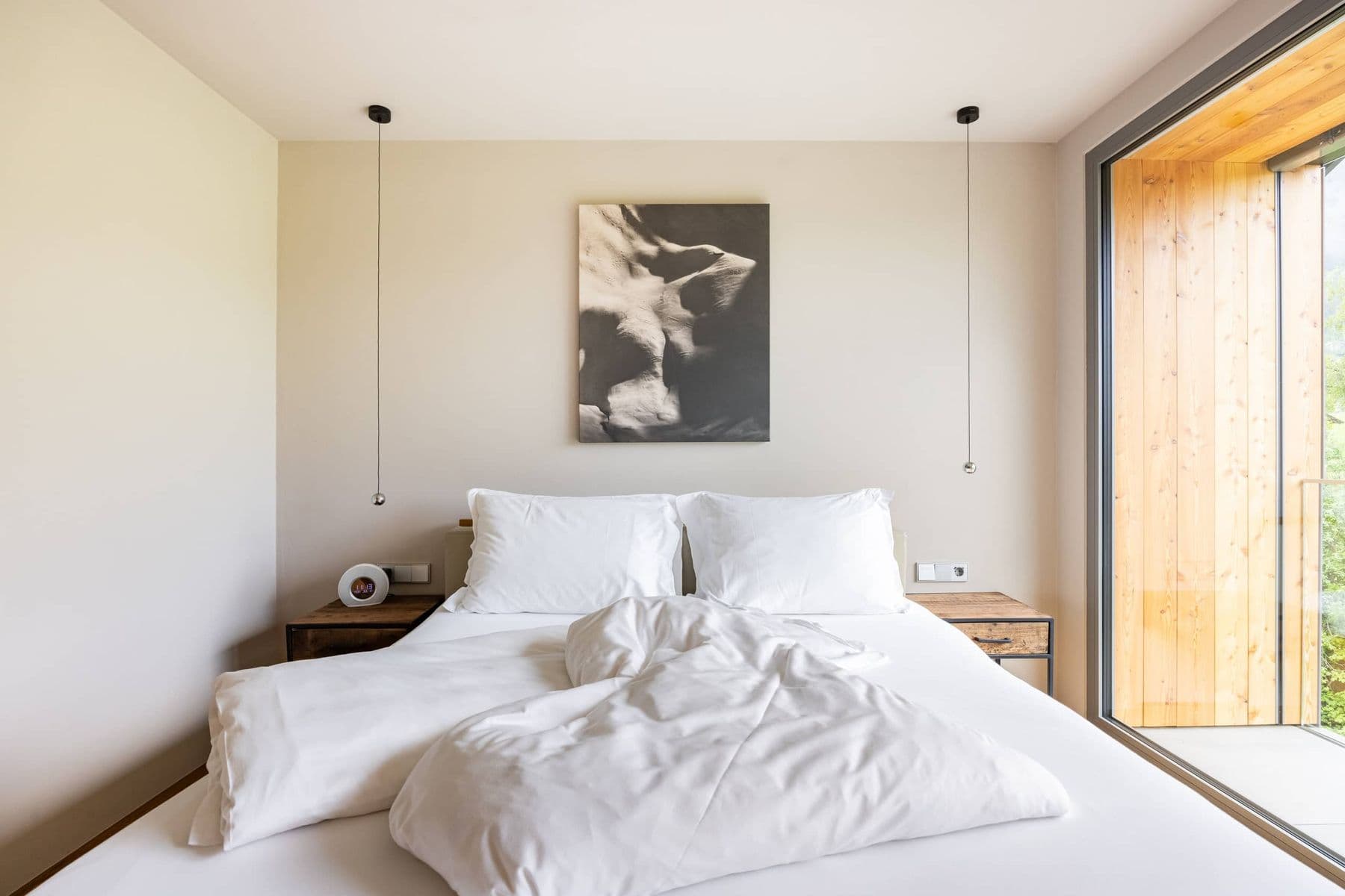 Helles Doppelzimmer mit grossem Doppelbett und raumhohem Fenster