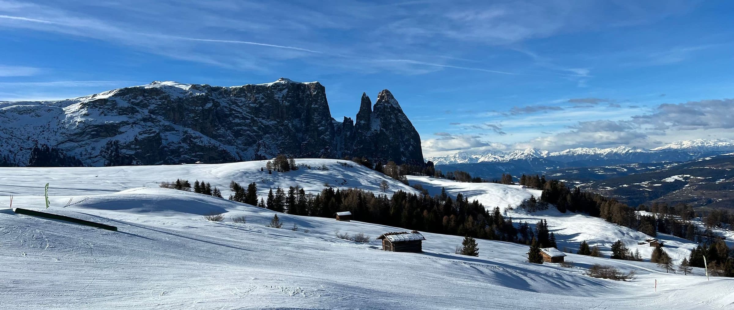Die verschneite Seiser Alm unter blauem Himmel, dahinter der Schlern