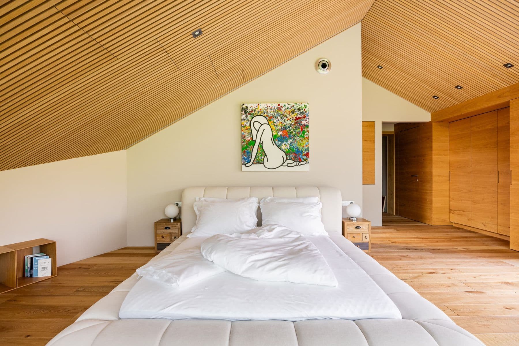 Grosses Doppelbett unter der Holzdecke der Suite